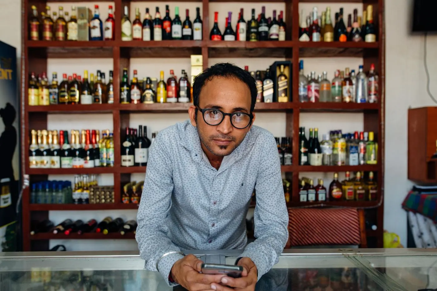 Dono de pequeno negócio mexendo no celular na loja