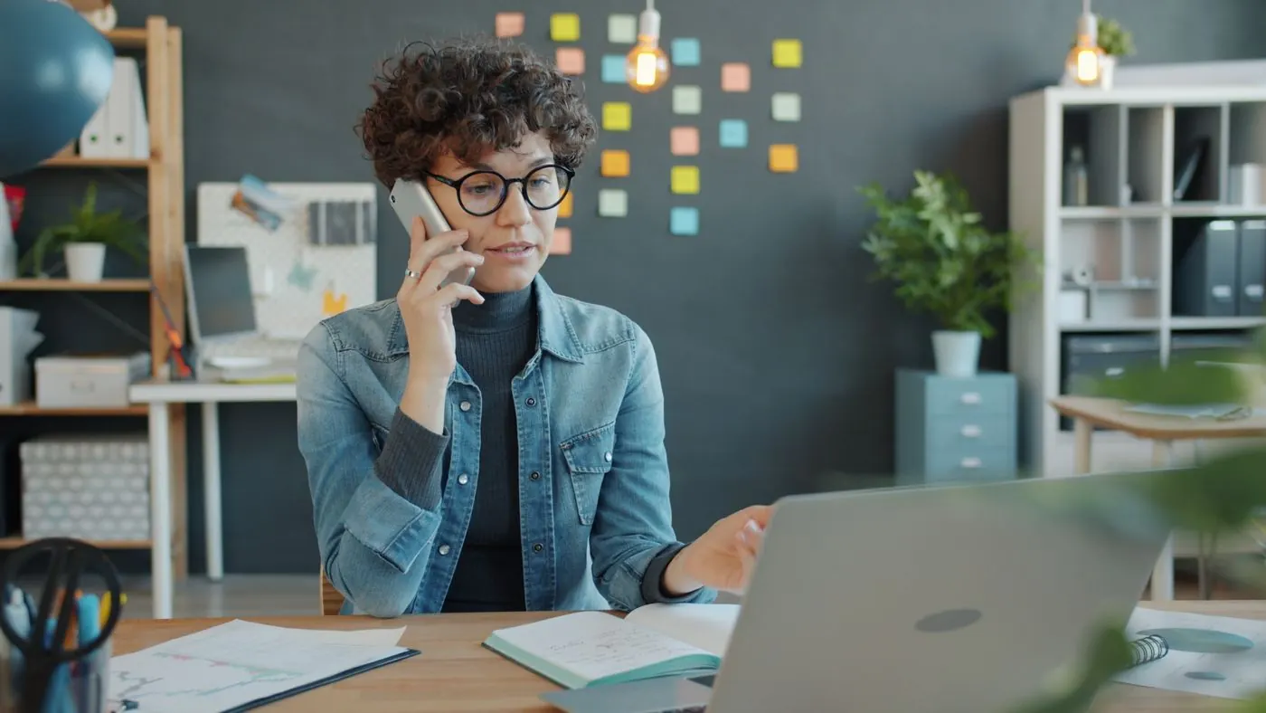 Dona de pequeno negócio mexendo no celular no escritório