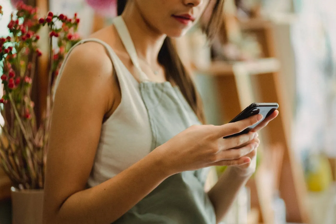 Dona de pequeno negócio mexendo no celular na loja